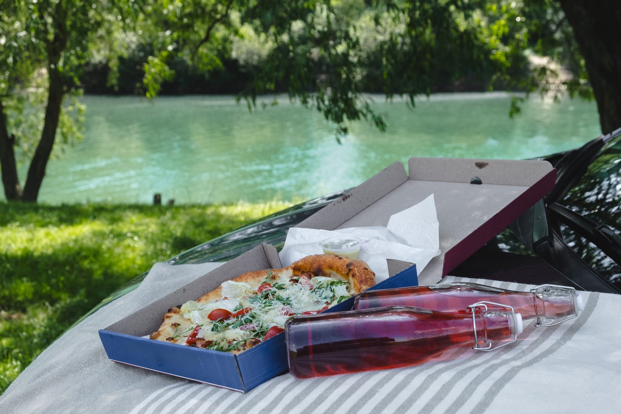 outdoors-picnic-pizza-with-drink-on-car-hood-at-th-2025-03-05-19-45-32-utc.jpg